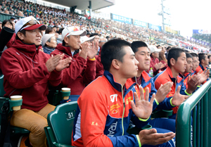 スタンドから行進する選手たちに拍手を送る日南学園野球部員と保護者ら